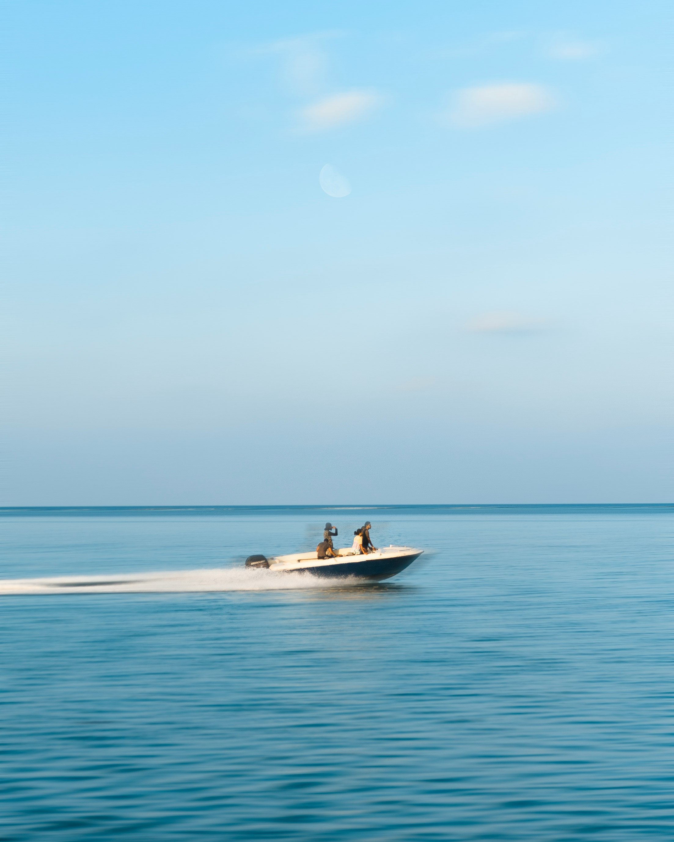 three person riding on motorboat under white clouds at daytime